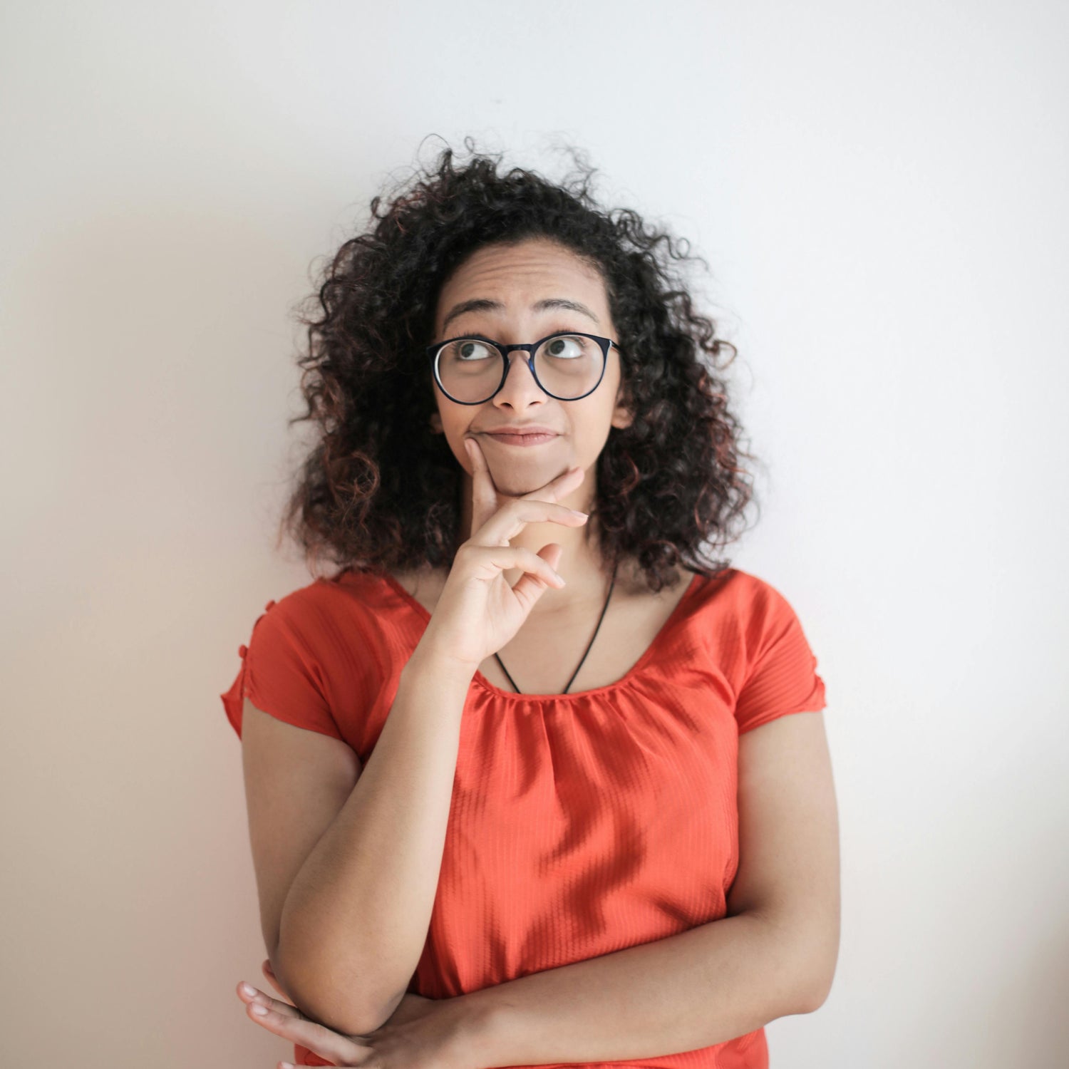 Woman wearing glasses and an orange top against a plain background