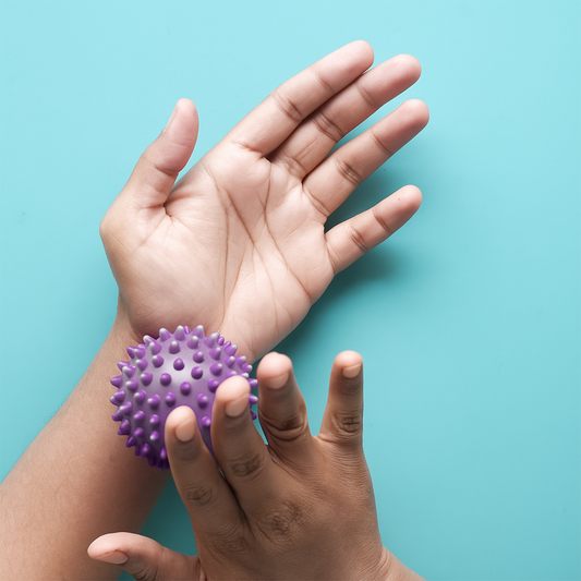 Using a purple massage ball on wrist for muscle relief – The Fit Fab Co

